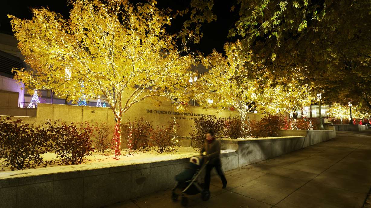 A woman pushes a stroller on the sidewalk near the Christmas Lights at The Church of Jesus Christ o...