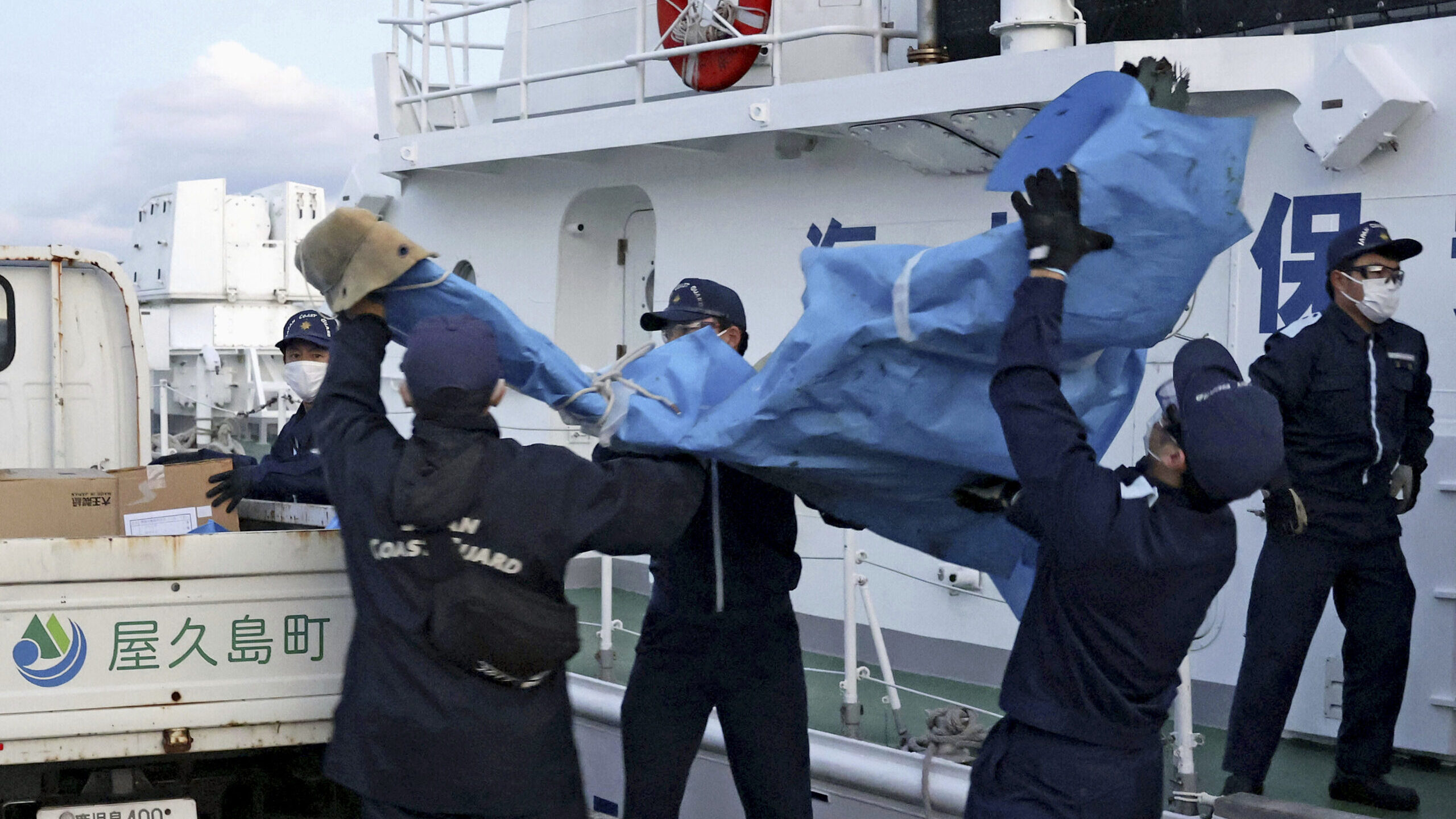 Image of members of Japanese Coast Guard carry the debris which are believed to be from the crashed...