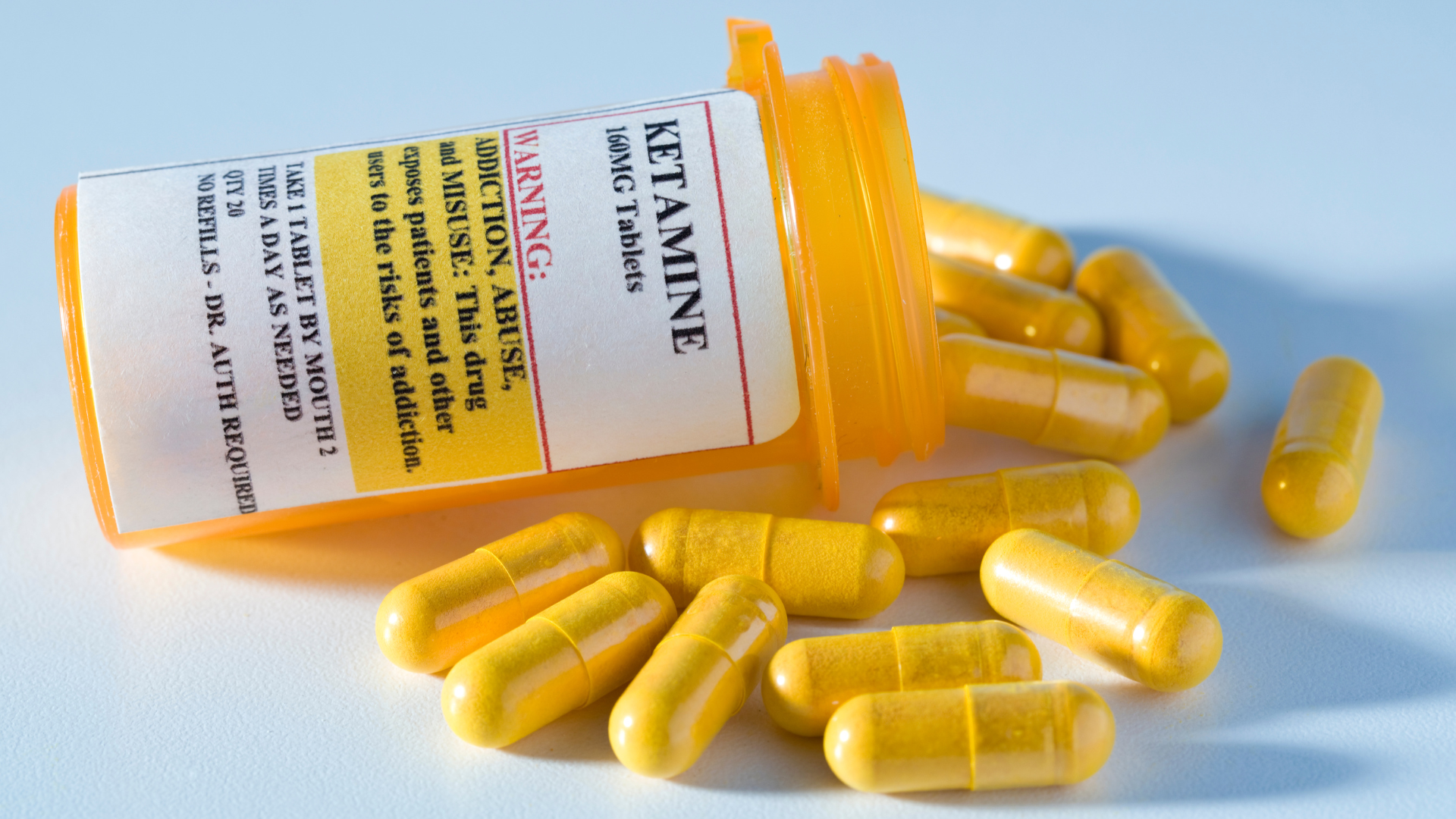 Yellow pills spill out of a bottle labeled 'ketamine.'...