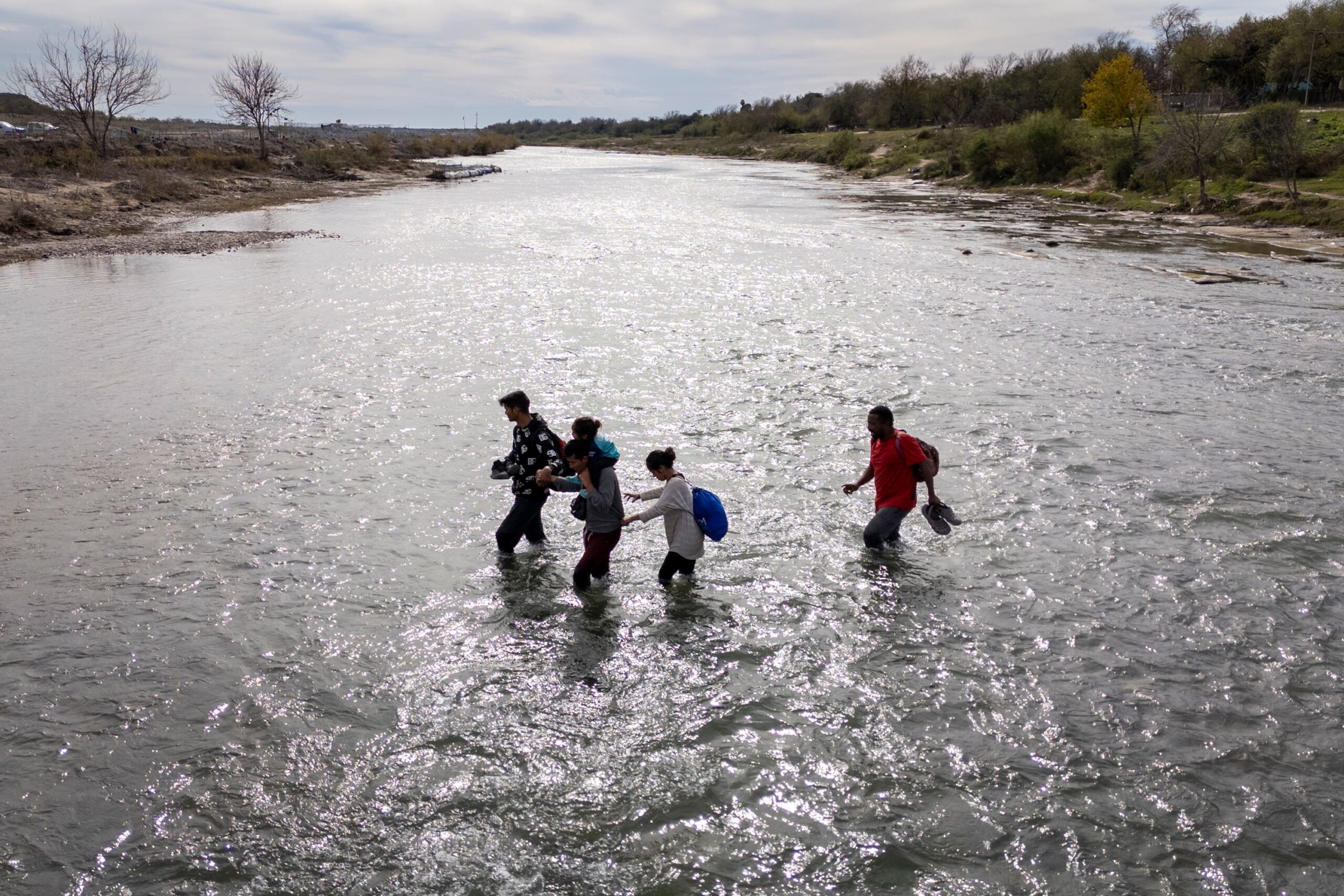 An immigrant family crosses to the American side of the Rio Grande on December 19, in Eagle Pass, T...