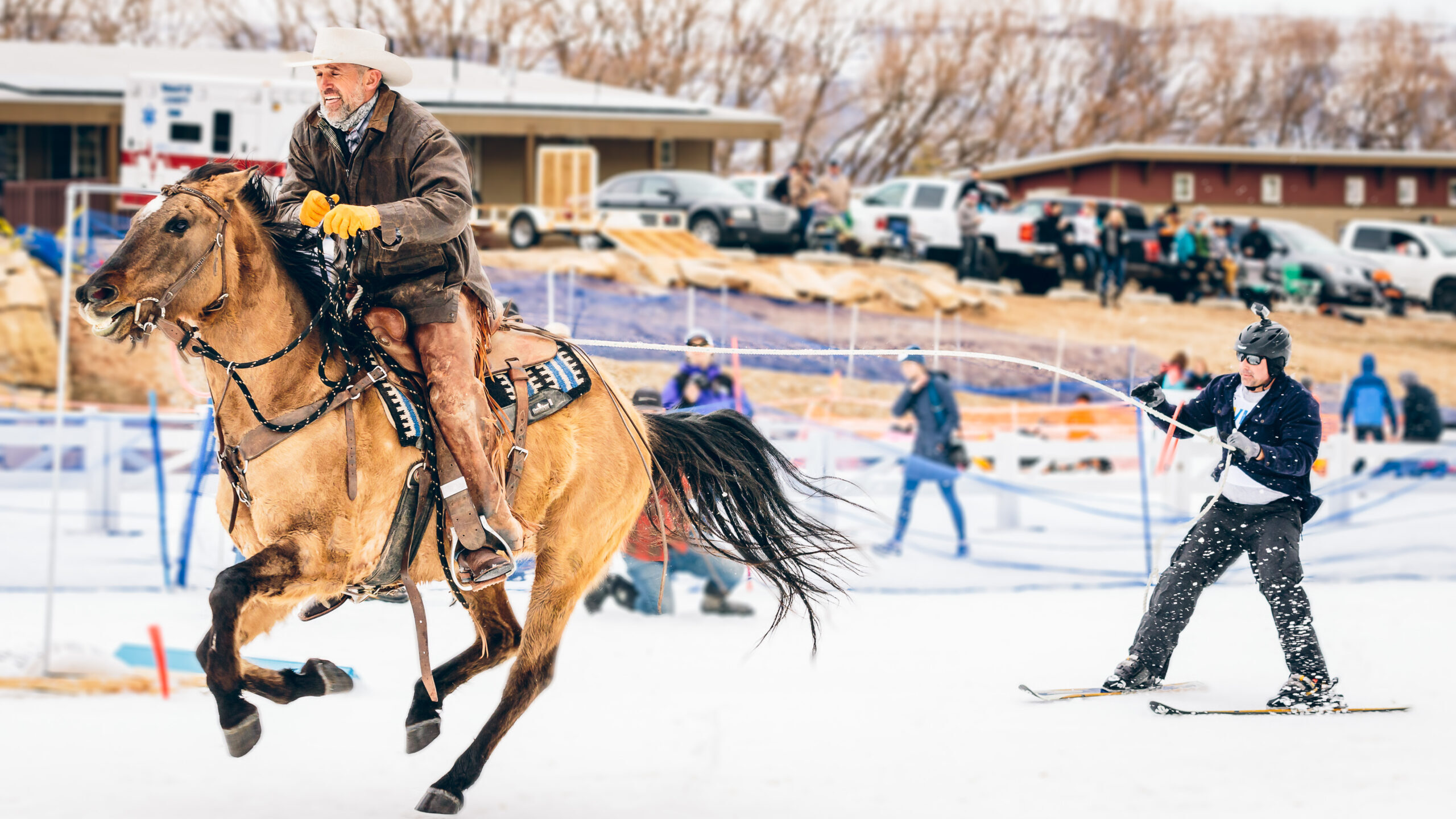 A person rides a brown horse while a skier is pulled behind....