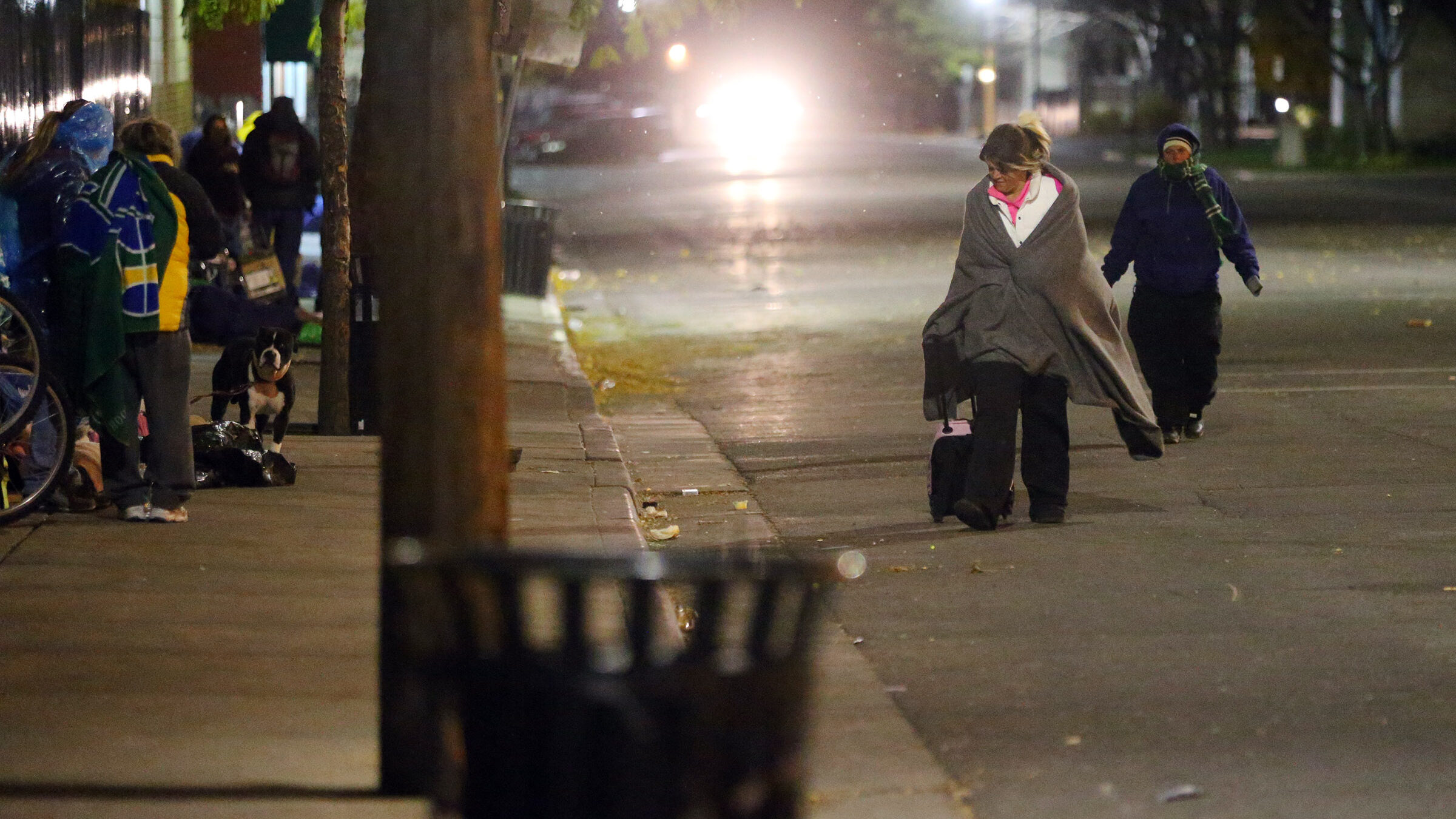 People experiencing homelessness walk in the street near a winter overflow shelter at St. Vincent d...