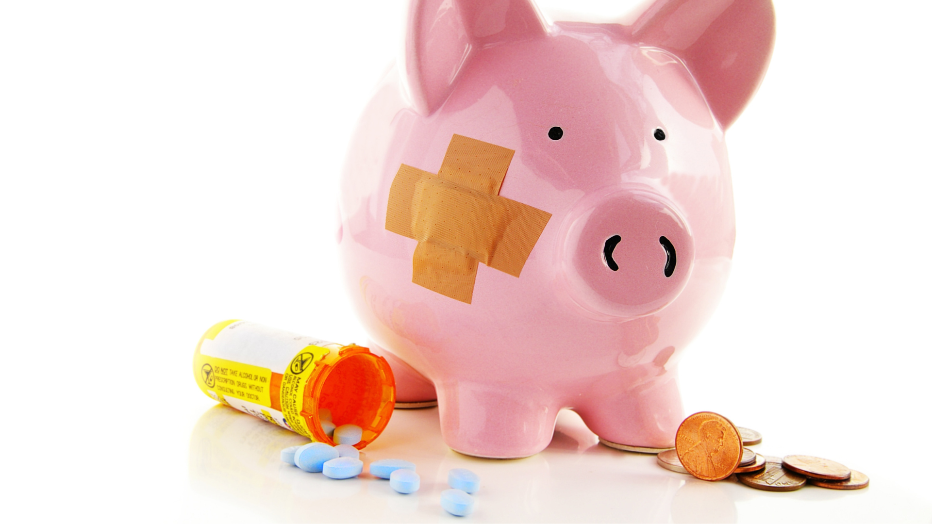 A bandaged piggy bank surrounded by blue pills spilling out of a prescription container. Coins sit ...
