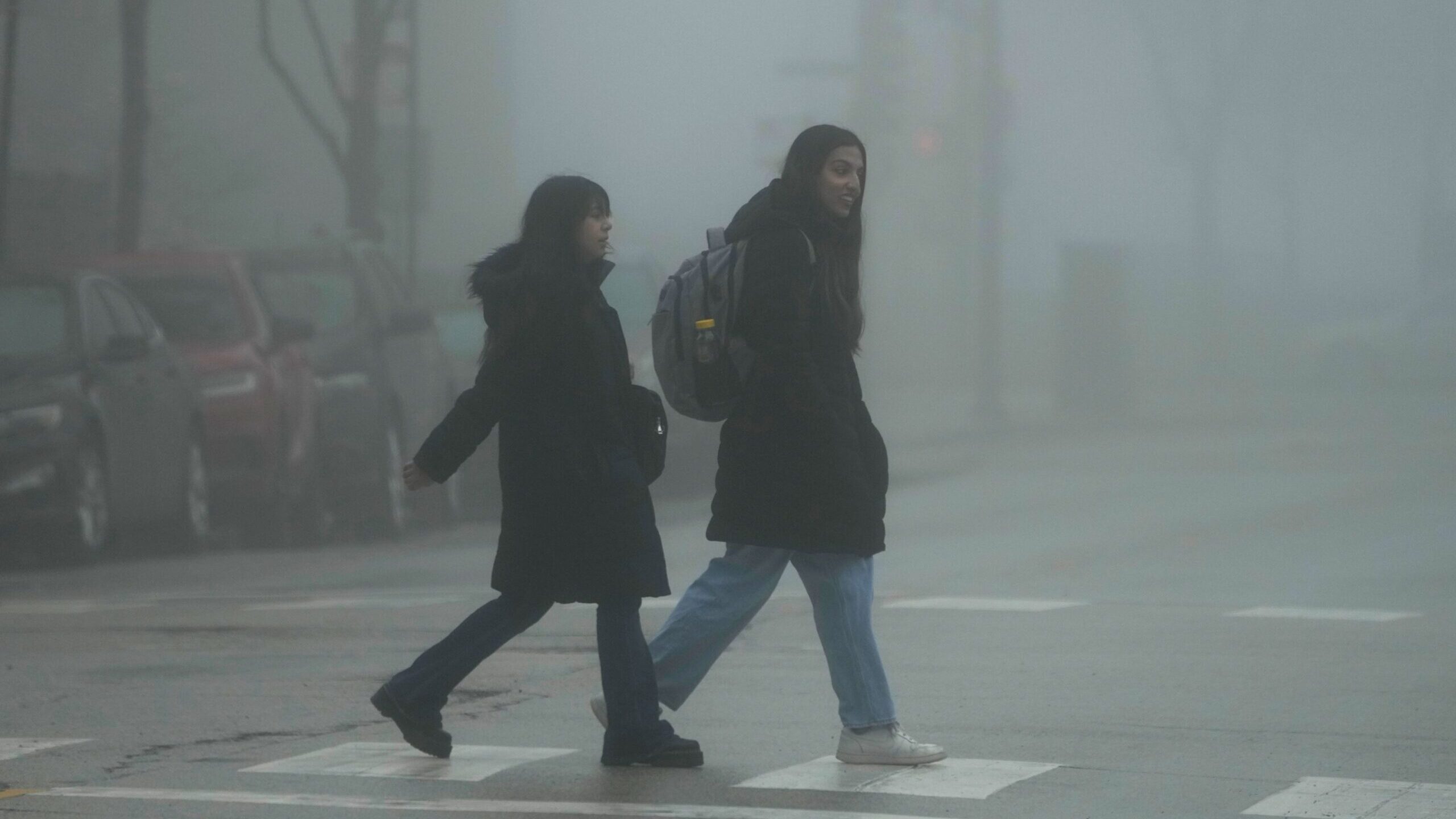 Pedestrians cross a street in the fog on Thursday, January 25, in Chicago....