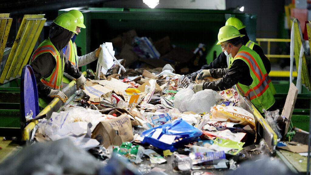 Workers hand-sort items from conveyors at the Waste Management sorting center in slc Utah, which de...