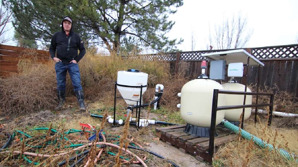 Kelby Johnson stands next to a sand filtration system for drip irrigation on his 100-acre farm in B...