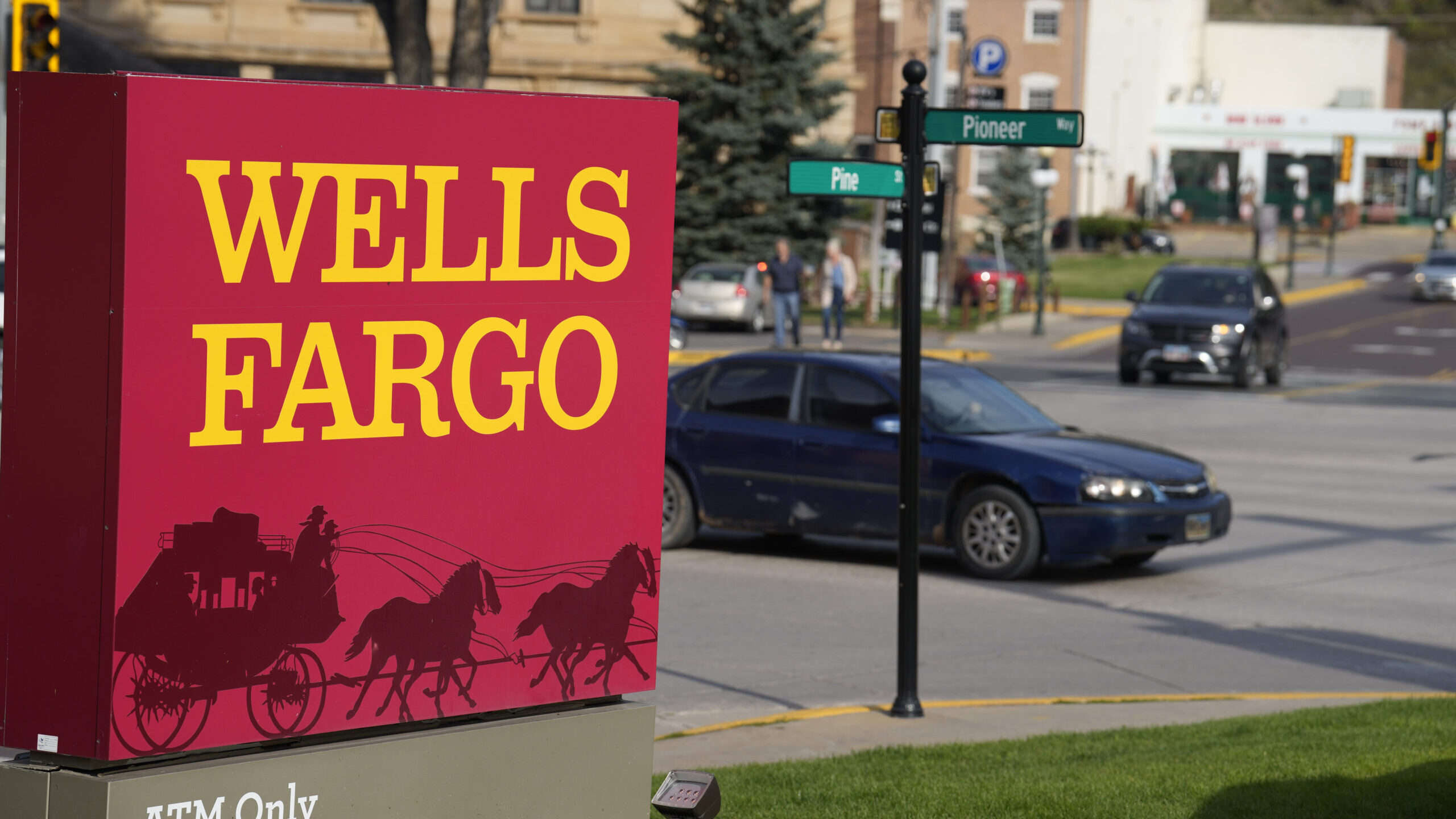 Motorists drive past a sign outside a branch of Wells Fargo bank, Wednesday, Sept. 20, 2023, in Dea...