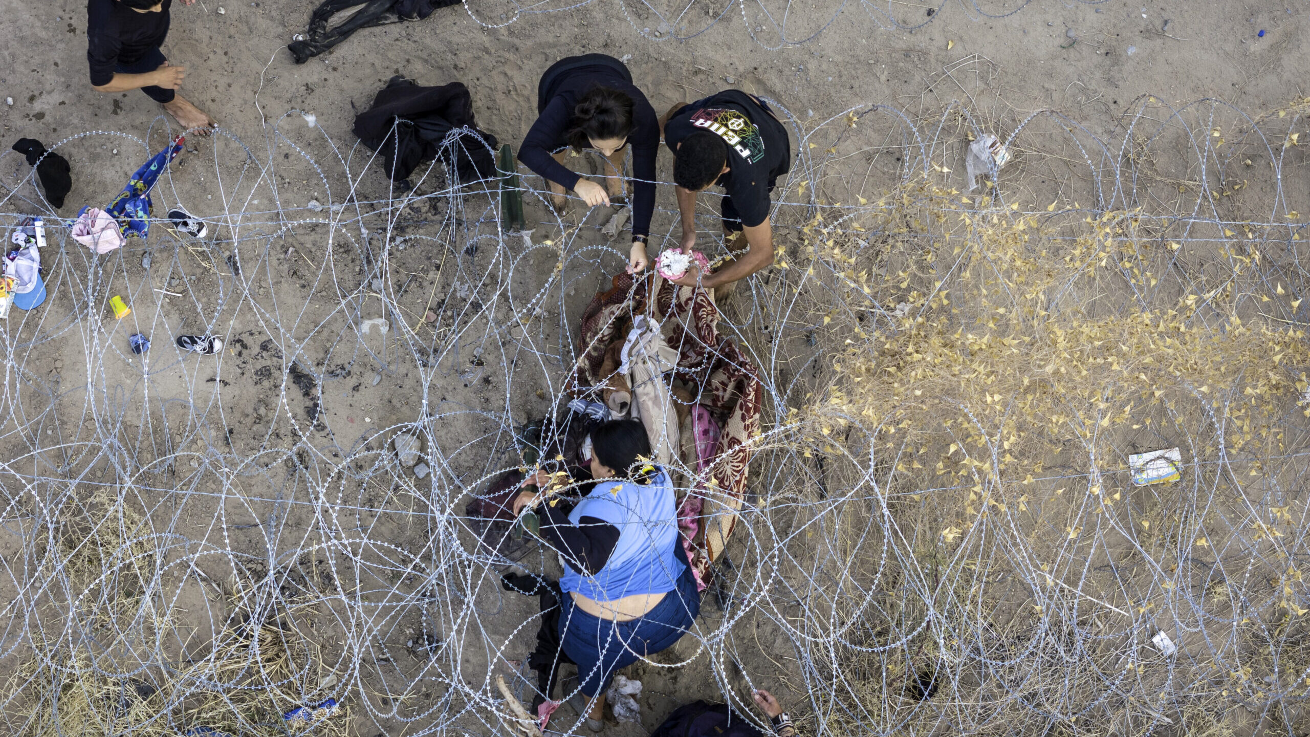 FILE: Seen from an aerial view, people pass through razor wire after crossing the U.S.-Mexico borde...