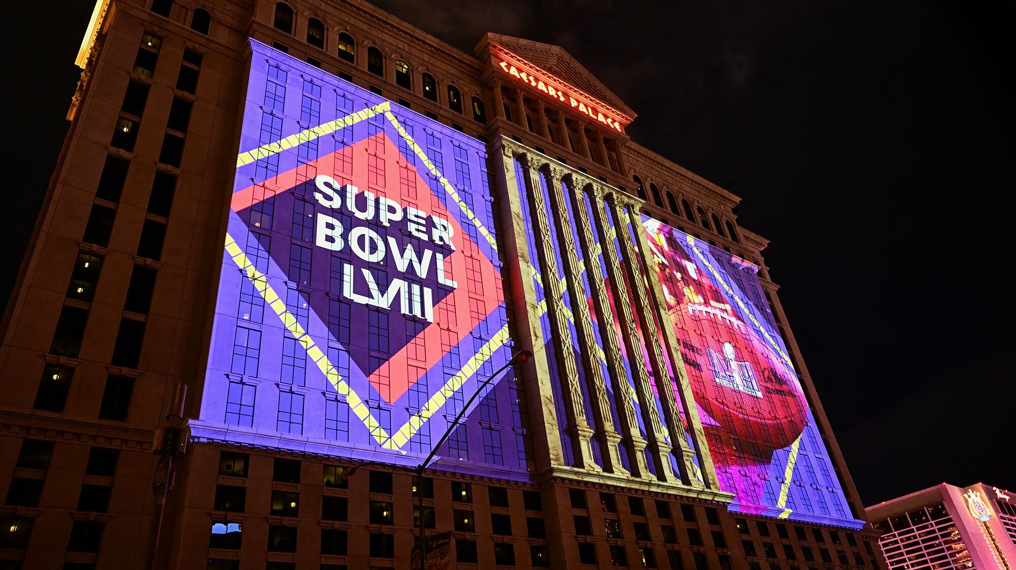 NFL Super Bowl LVIII football logos are projected on the side of Caesars Palace Las Vegas Hotel and...