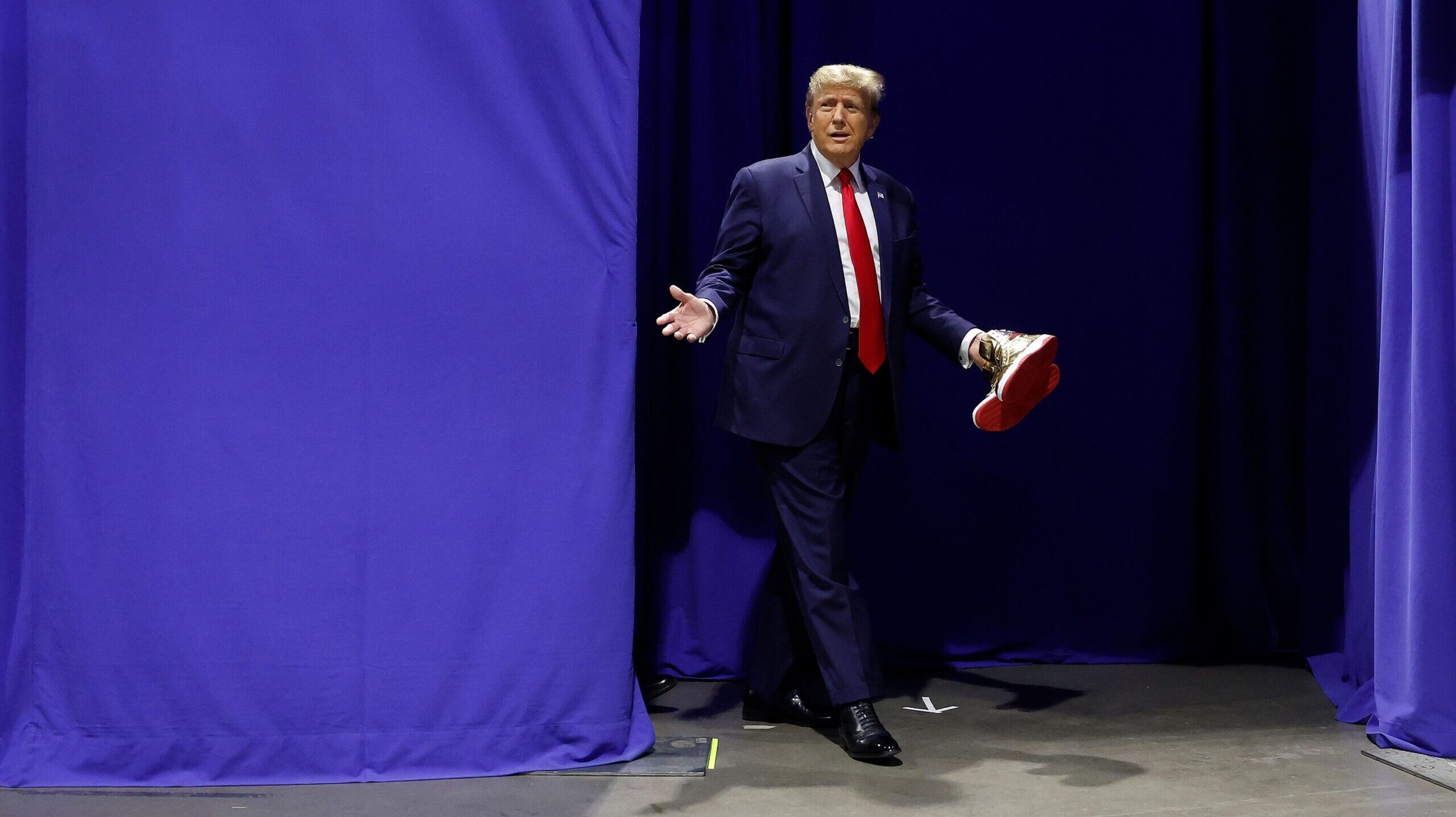 Republican presidential candidate and former President Donald Trump carries a pair of his new signa...