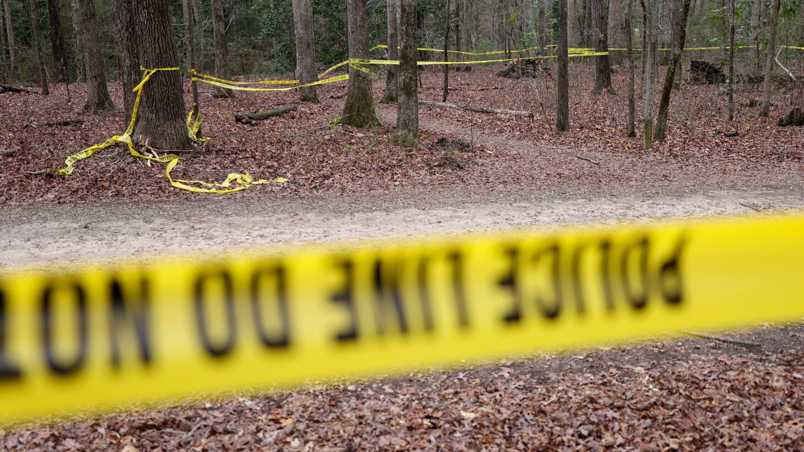 Police tape drapes the crime scene on a trail behind Lake Herrick at the University of Georgia in A...
