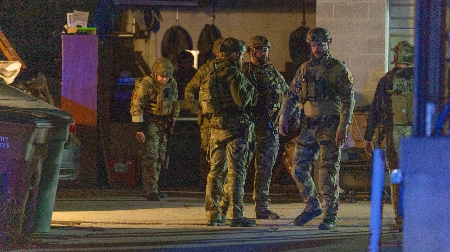 SWAT officers with the Salt Lake City Police Department stand in a driveway after they and patrol o...