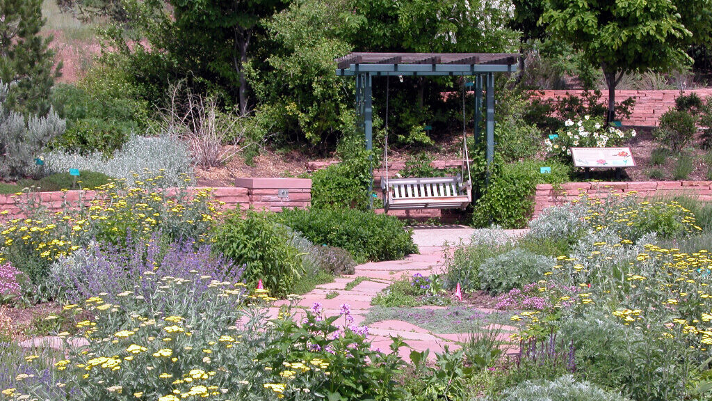 A bench sits surrounded by colorful, thriving plants in Salt Lake City's Red Butte Garden...