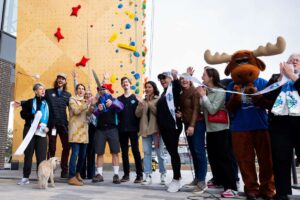 Millcreek Mayor Jeff Silvestrini is joined by City Council members, sponsors, and others in the ribbon-cutting at the grand opening of an outdoor climbing wall outside Millcreek City Hall on Saturday.
