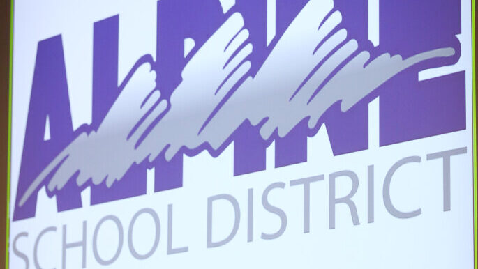 The purple Alpine School District logo is projected onto a white background...