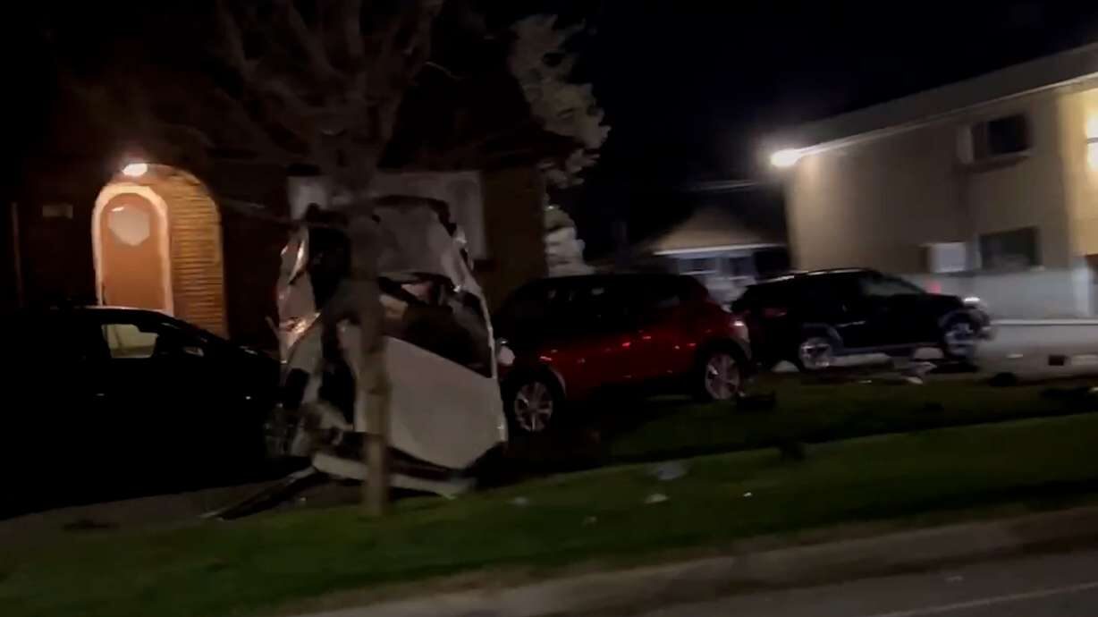 A wrecked white car sits on a green lawn at night....