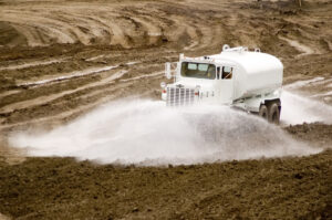 construction truck spraying water on dirt