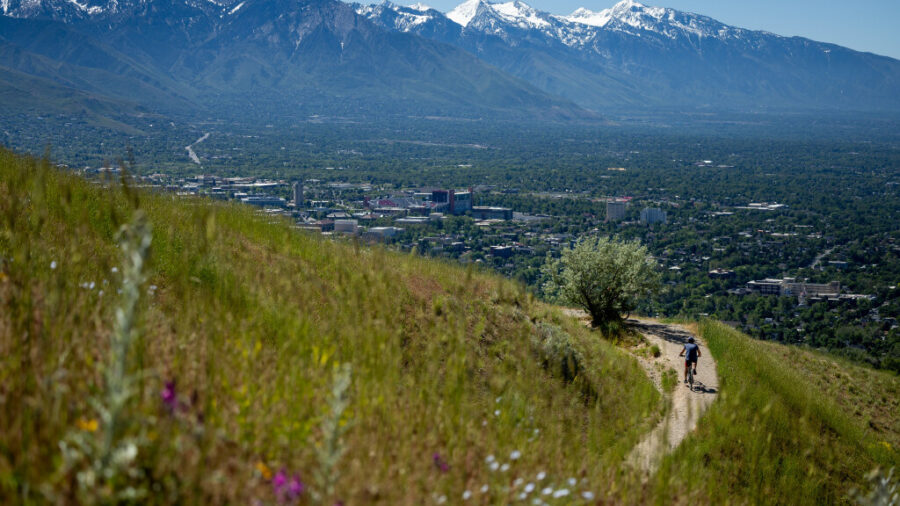 FILE: Green grass and wildflowers grow as a cyclist rides on the Bonneville Shoreline Trail in the ...