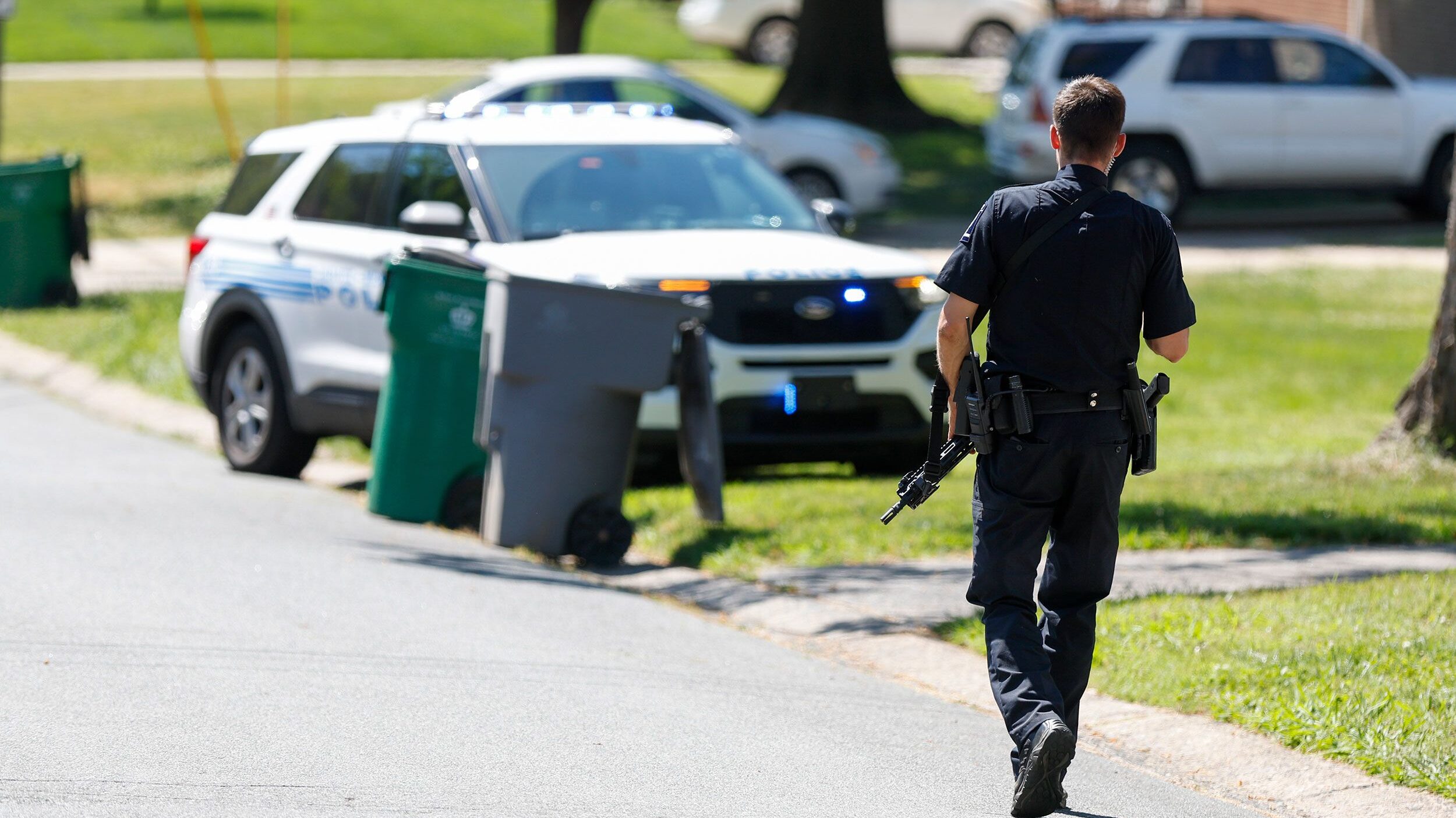 A Charlotte Mecklenburg police officer walks carrying a gun in the neighborhood where a shooting to...