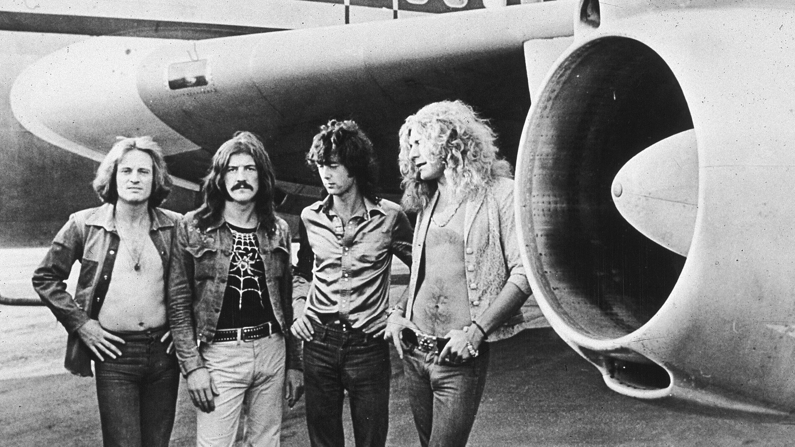 The members of Led Zeppelin pose in front of their private jet....