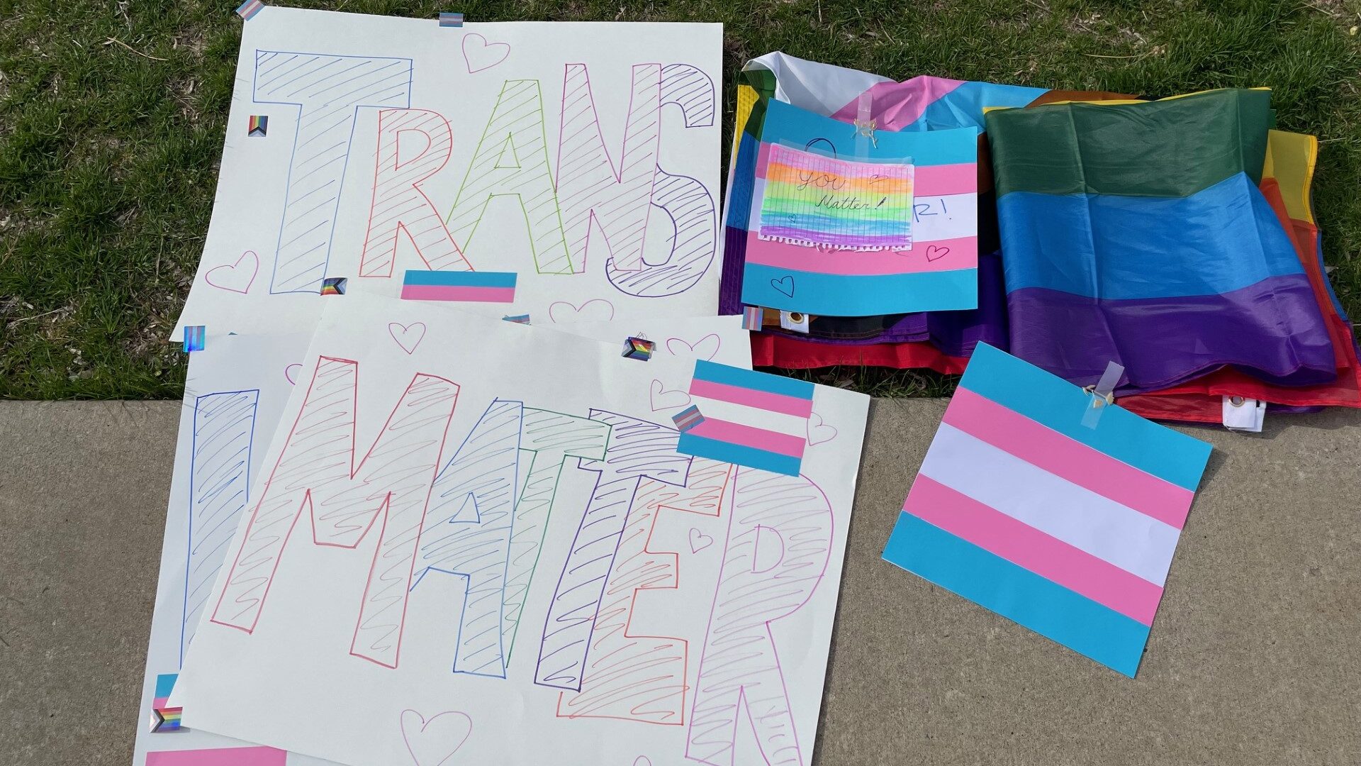 sign says "trans lives matter," the sign was for a protest about how slc school district was implem...