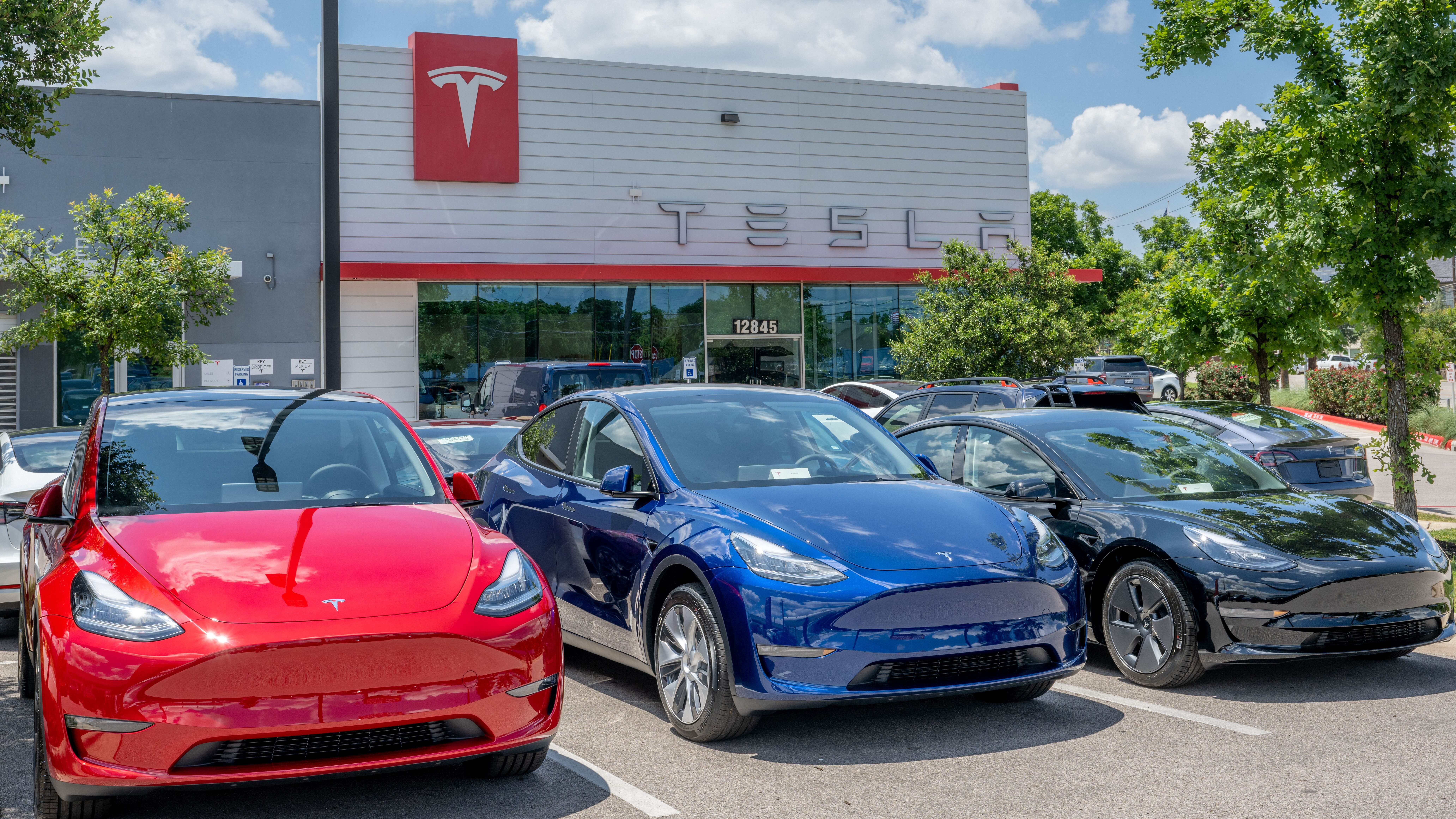 Tesla Model Y vehicles sit on the lot for sale at a Tesla car dealership in May 2023 in Austin, Tex...