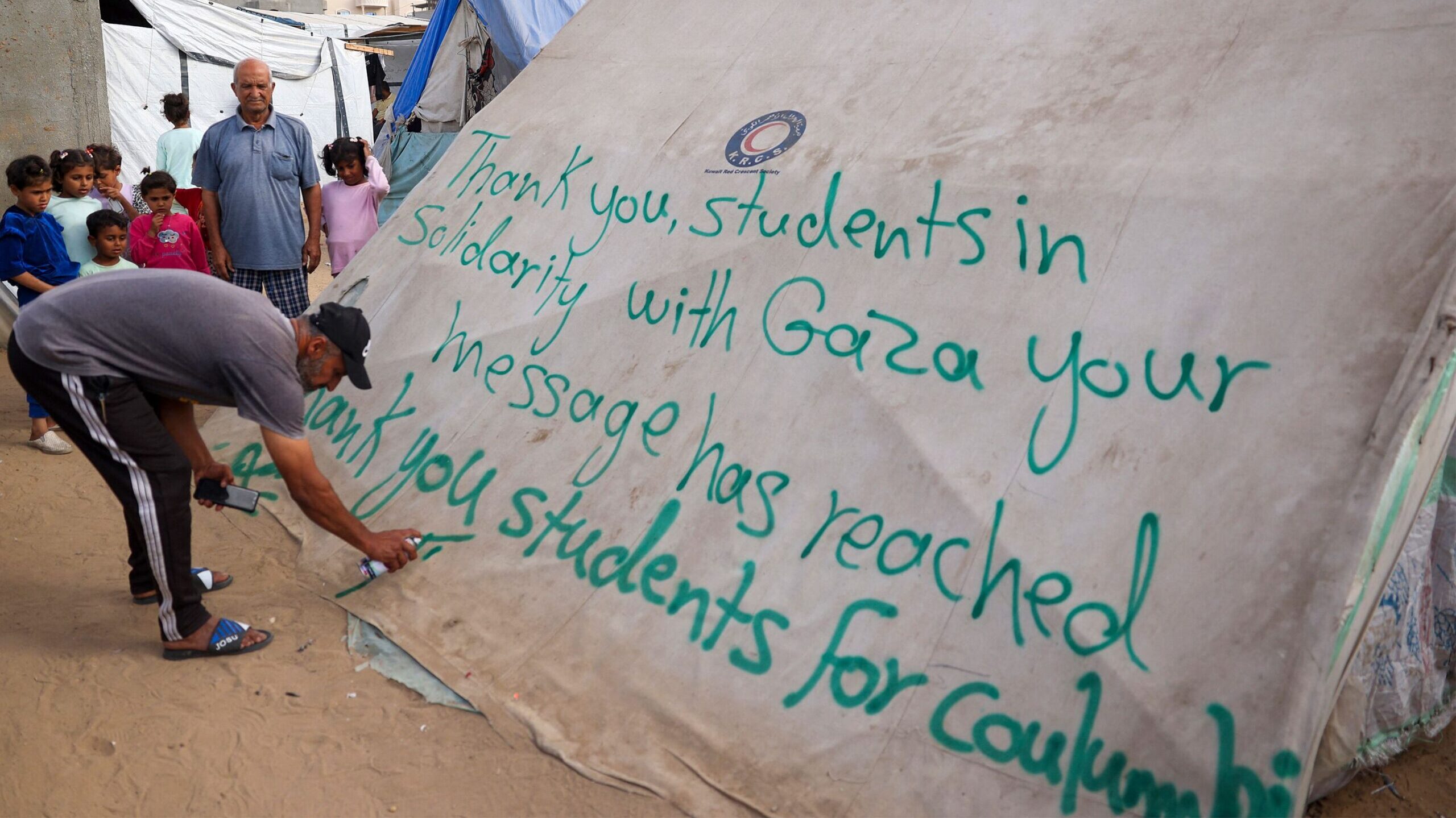 A man in Rafah, Gaza, writes a message of thanks to student protesters in the US on Saturday, April...