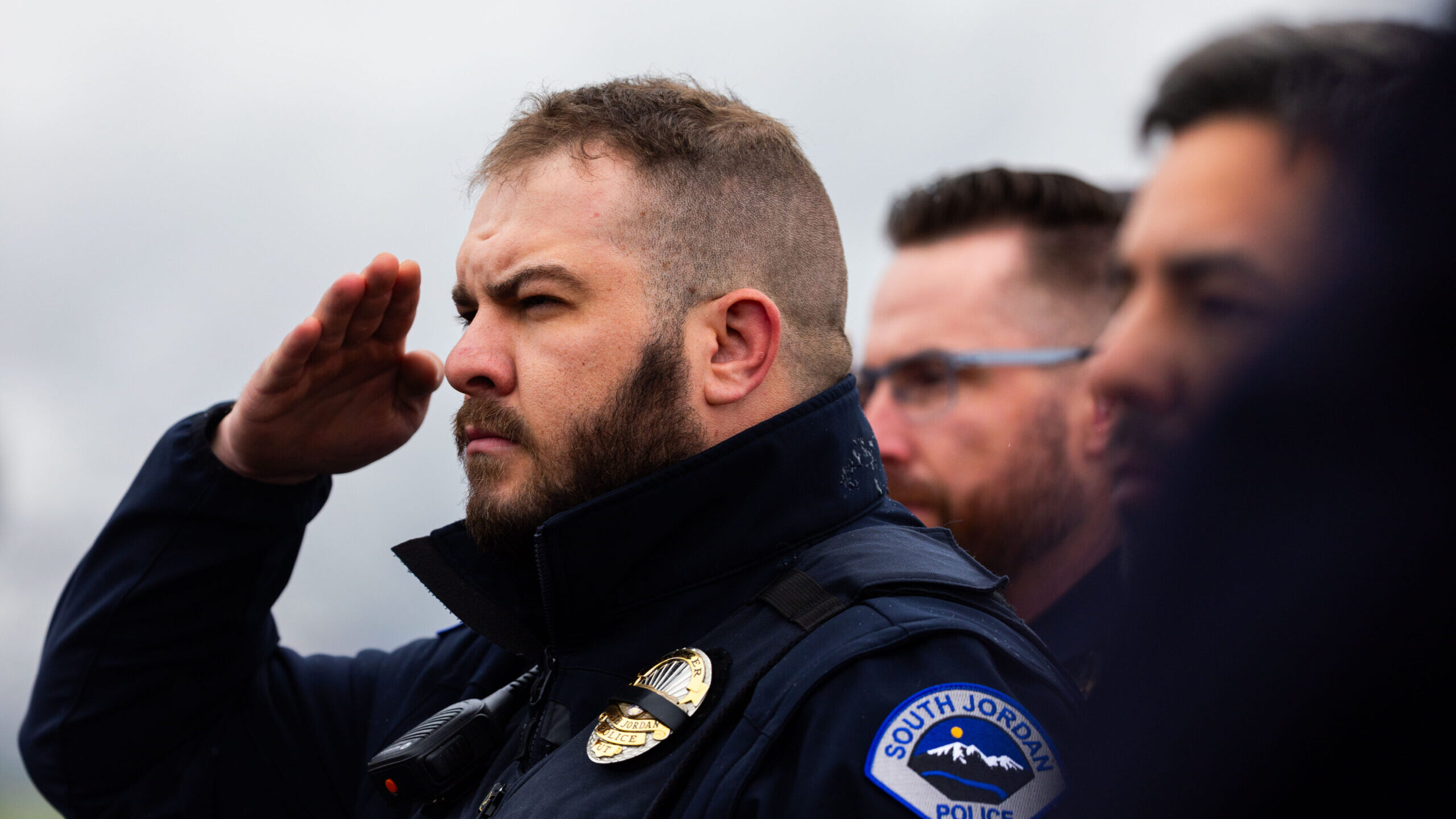 Officer Jeffrey Cox of the South Jordan Police Department salutes as a procession with the body of ...
