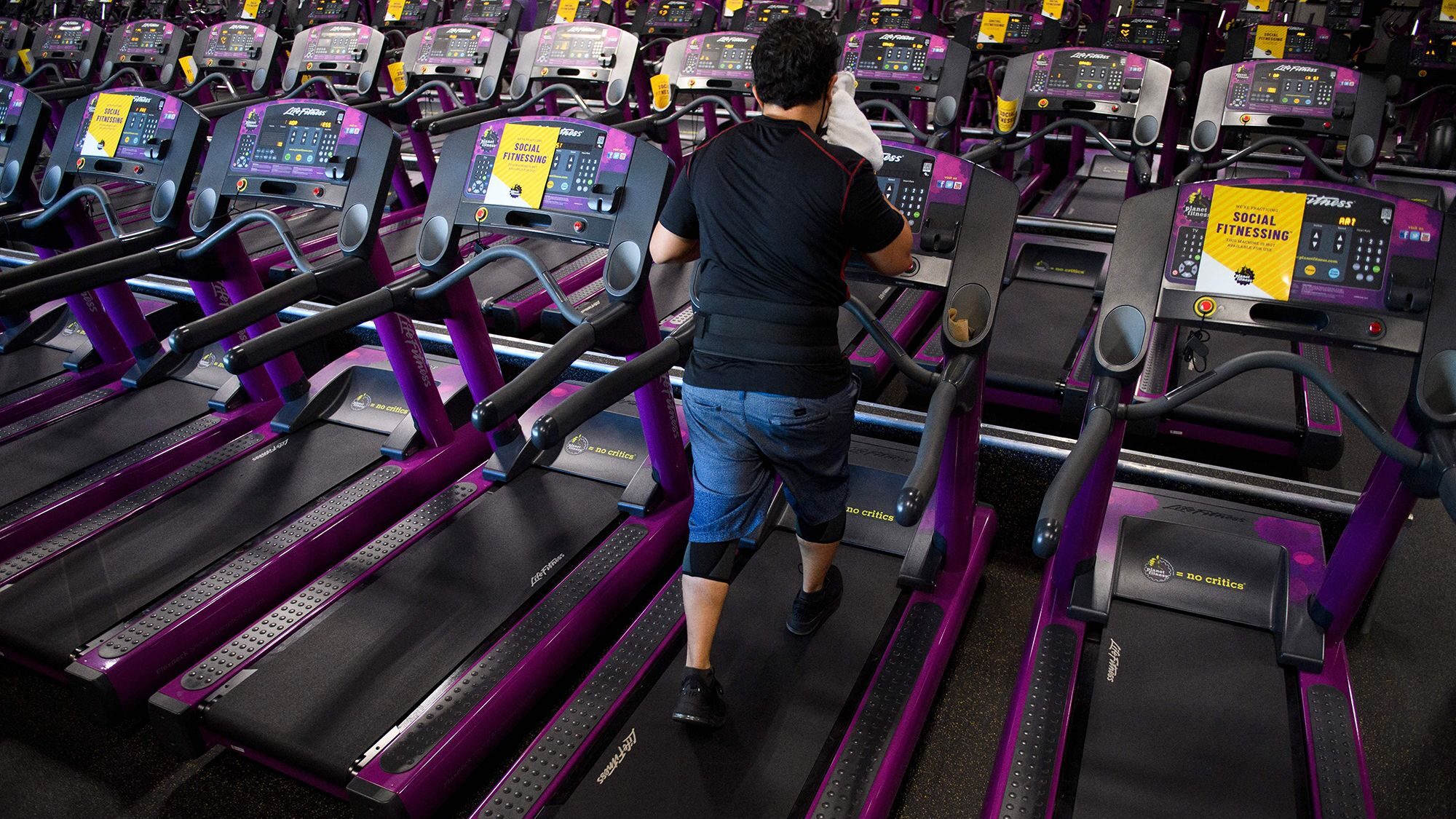 A customer wipes sweat from their face as they work out on a treadmill inside a Planet Fitness Inc....
