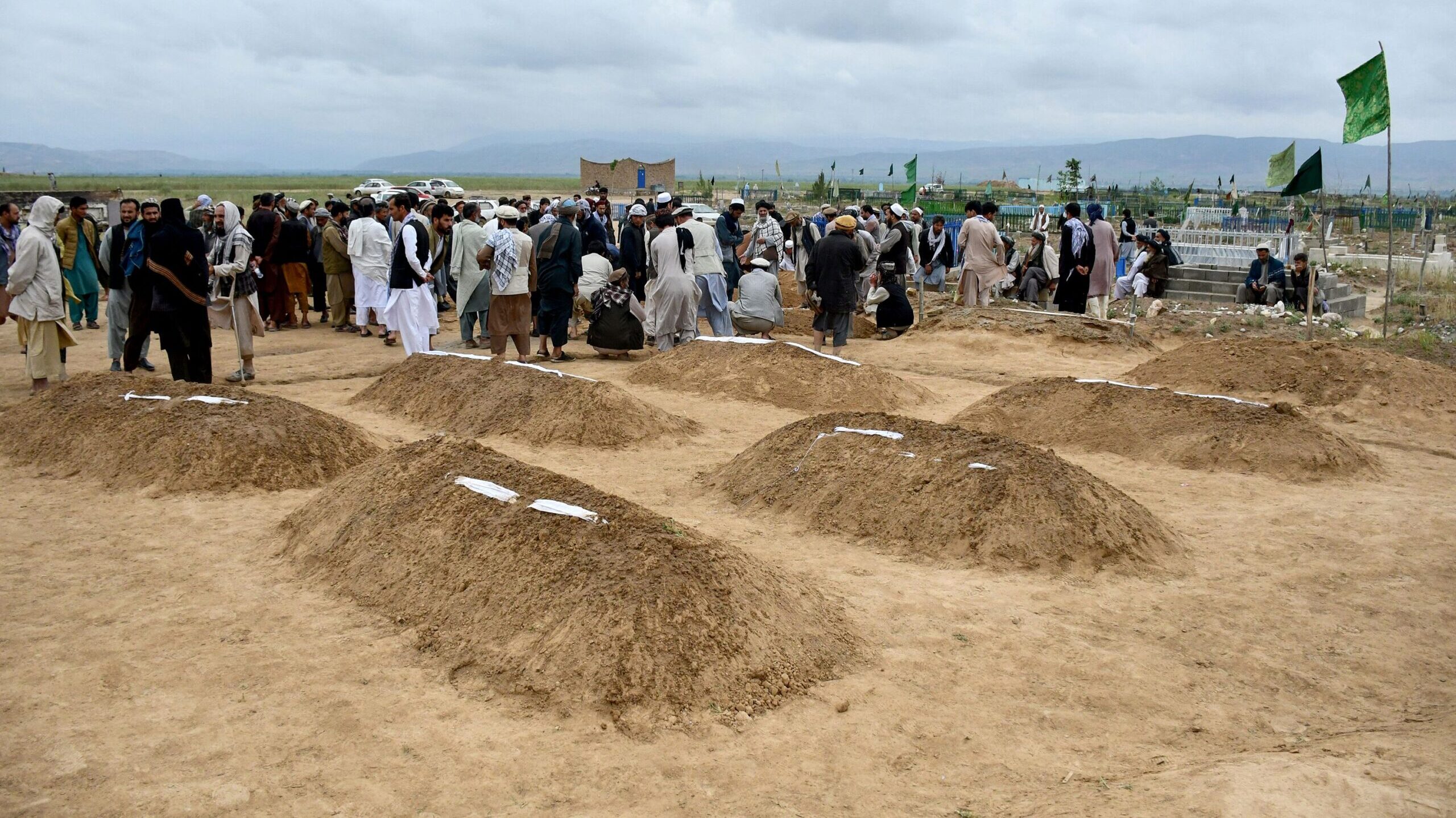 Afghan relatives offer prayers during a burial ceremony near the graves of victims who lost their l...