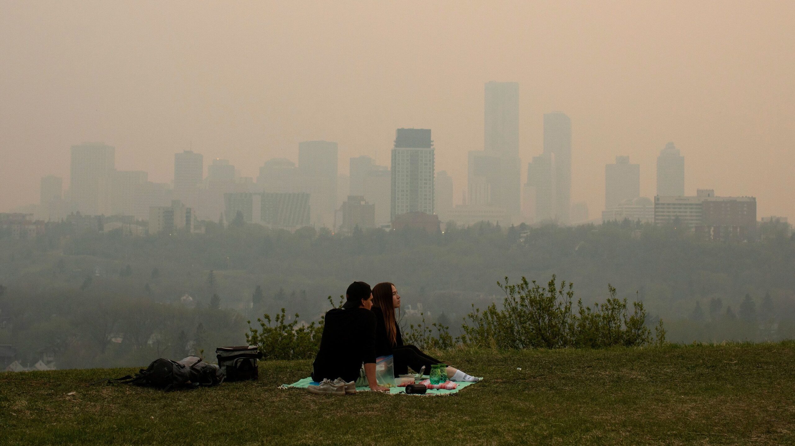 Smoke from wildfires blankets the city as a couple has a picnic in Edmonton, Alberta, Saturday, May...