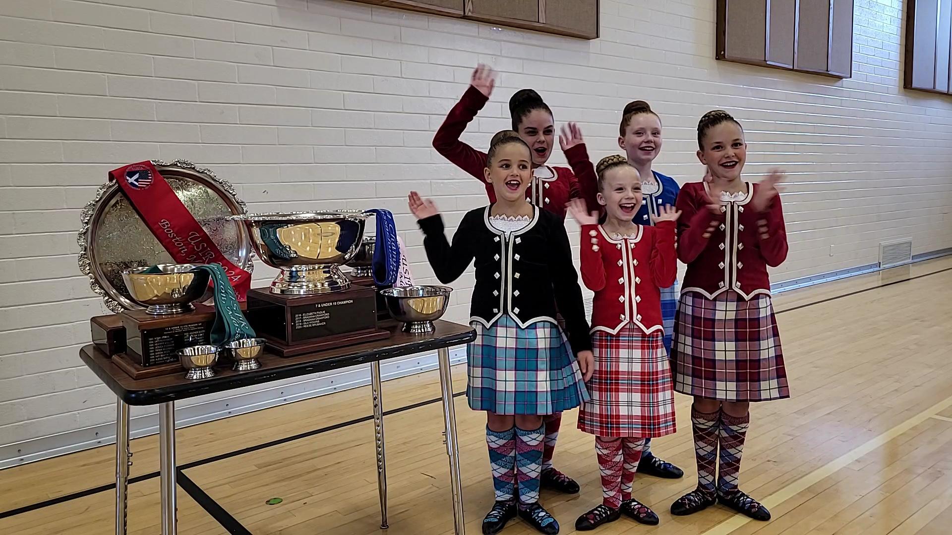 The five award-winning dancers from the Crane School of Highland Dance cheer next to their trophies...