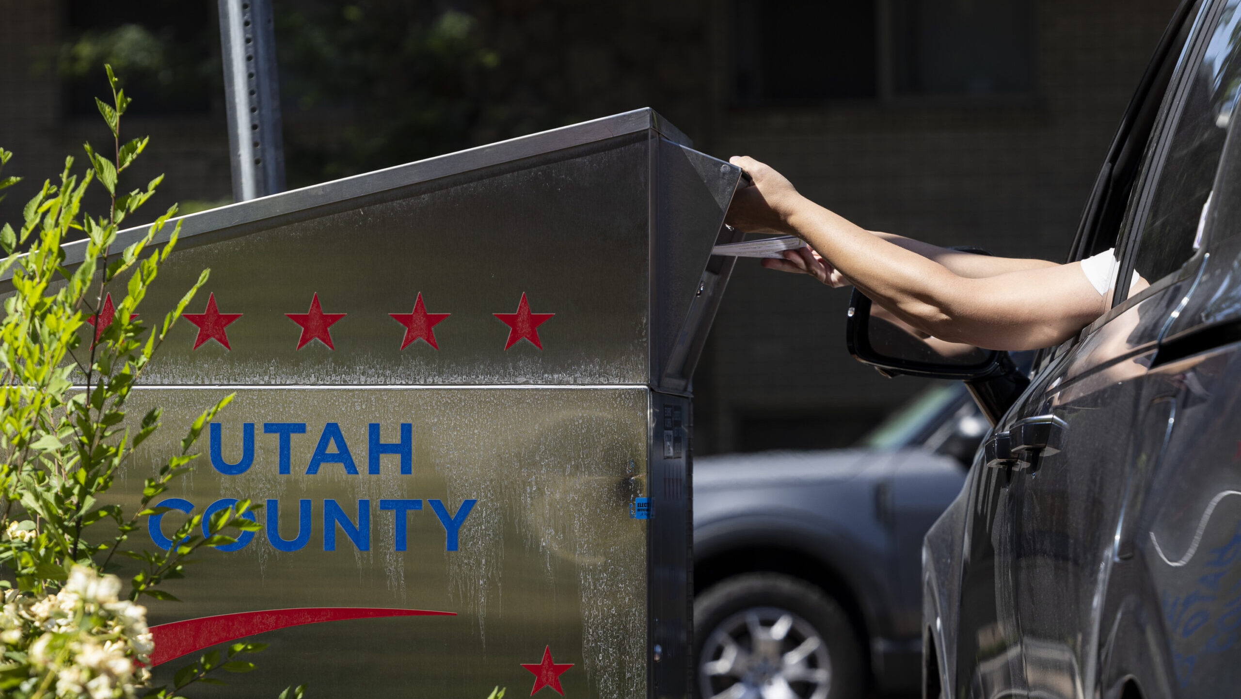 A voter drops their ballot in a ballot drop box during primary election voting at the Orem Public L...