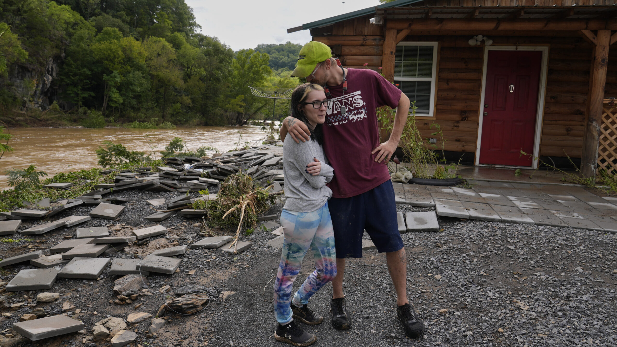 Jonah Wark, right, kisses his wife Sara Martin outside their flood-damaged home on the Pigeon River...