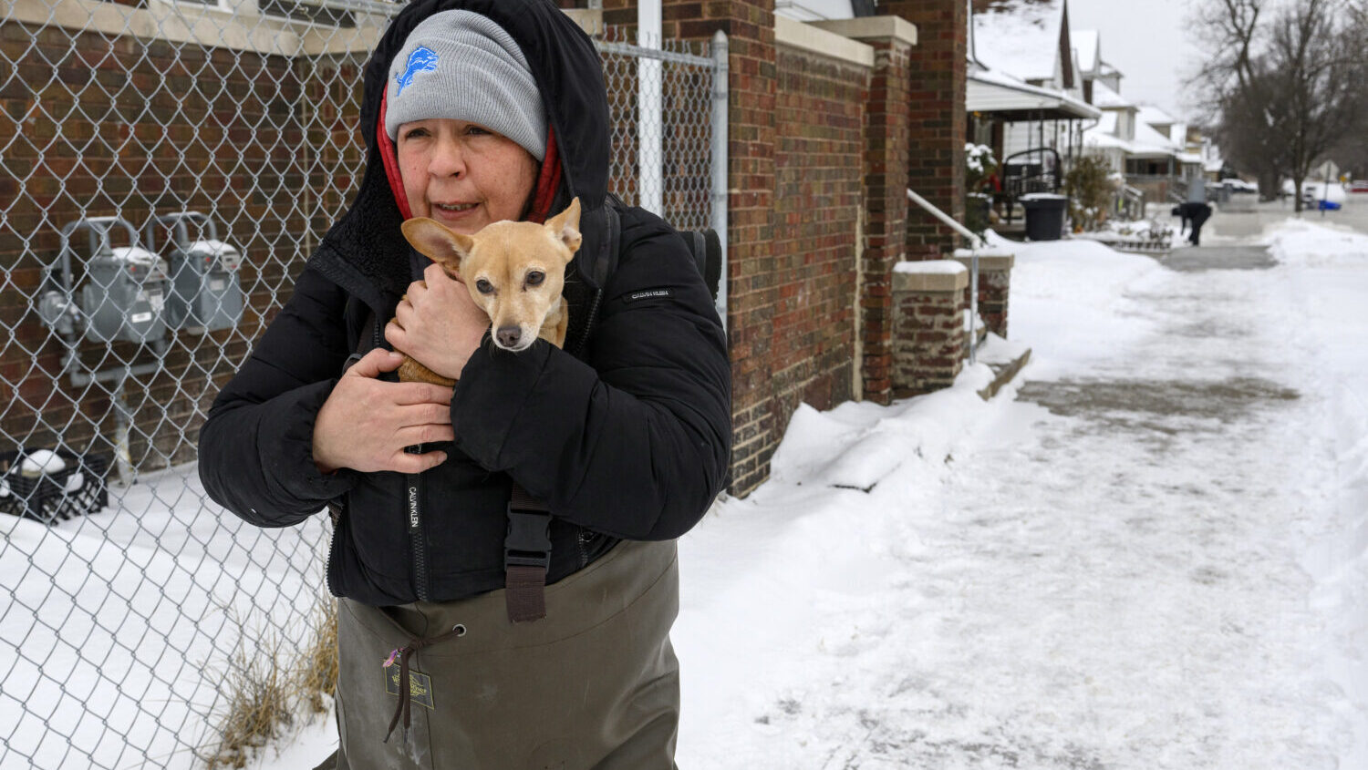 Lisa Muscat carries her dog Zoey to safety after a water main break in Detroit caused massive flood...
