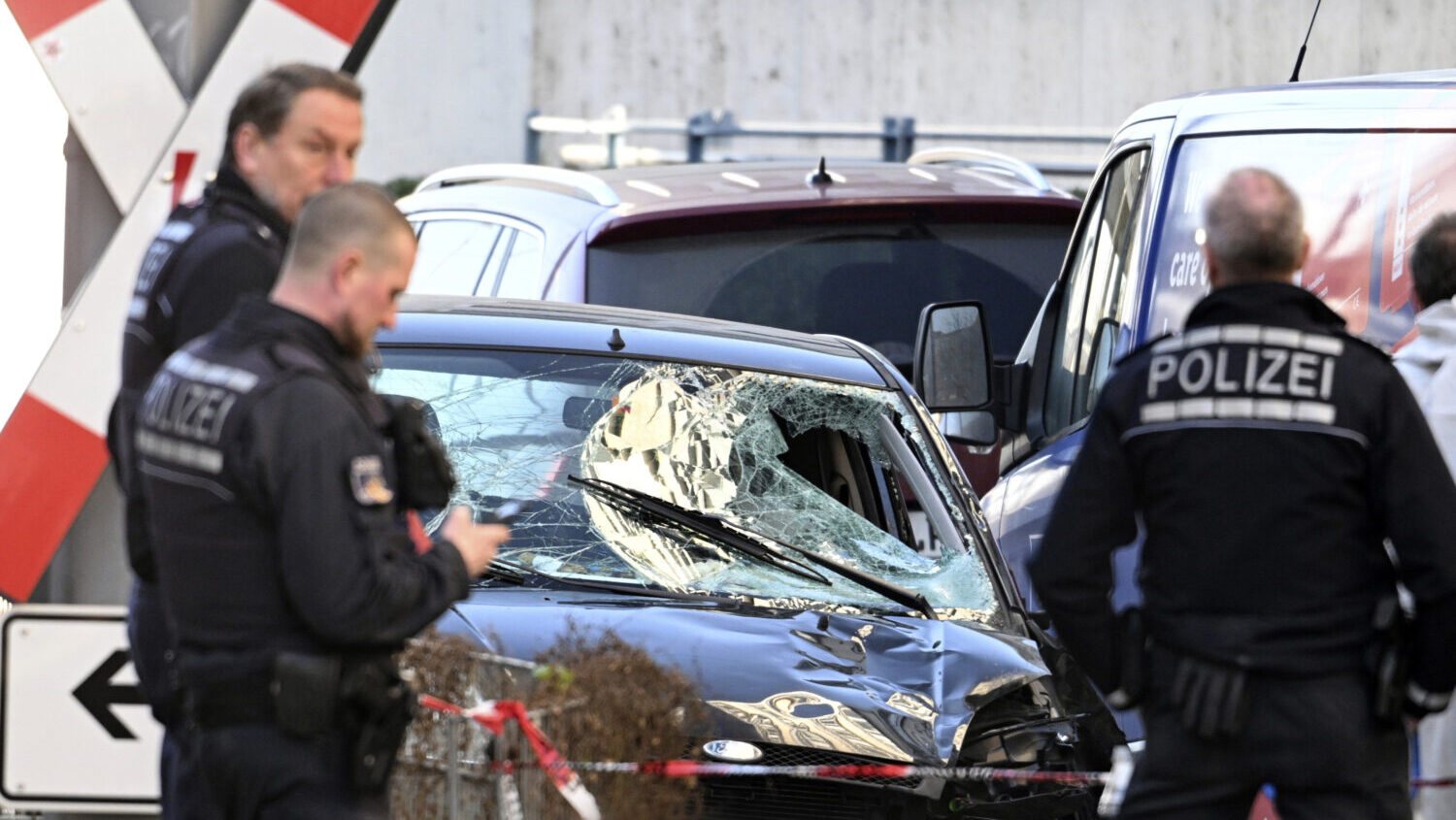 Police officers stand next to a damaged vehicle in the city center of Mannheim, Germany, Monday Mar...