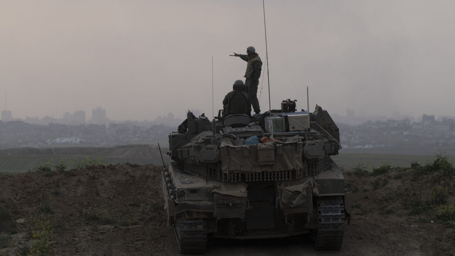Israeli soldiers stand on a tank as it is taking position in front of the northern Gaza Strip as se...