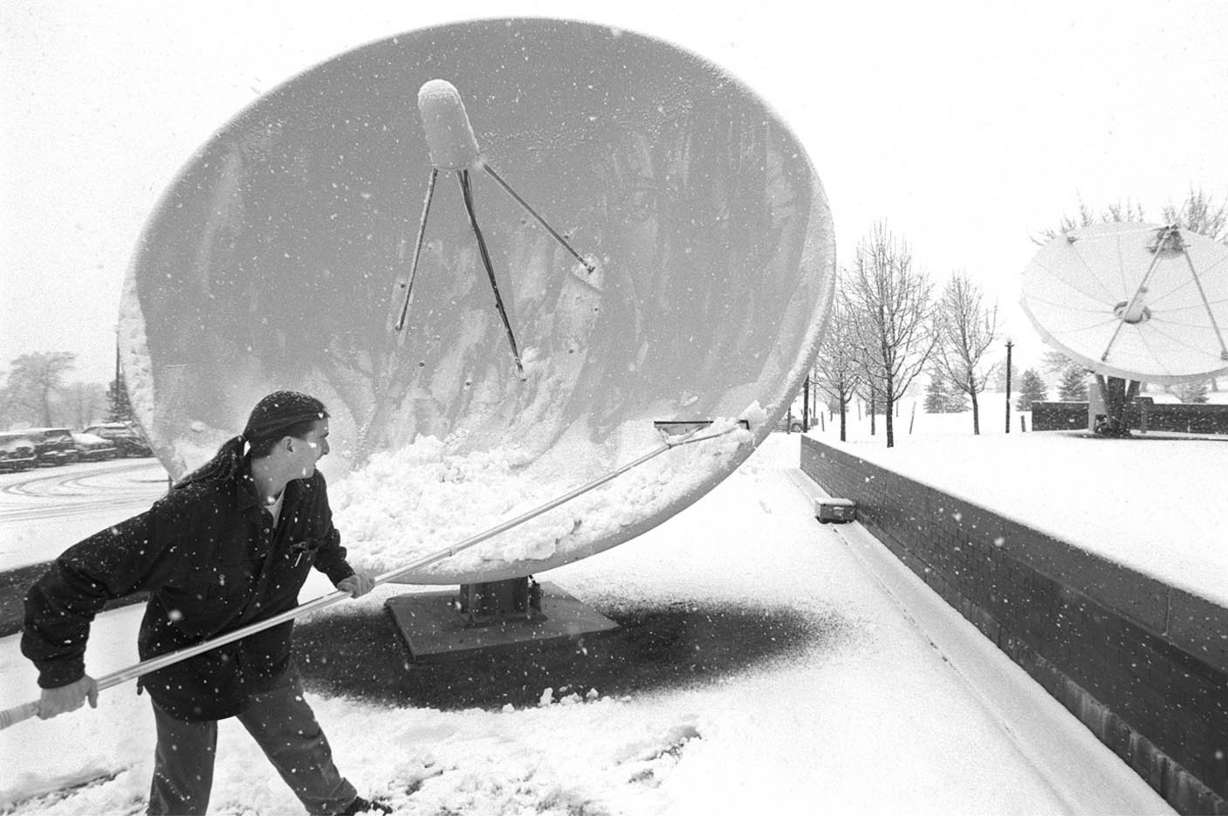 James Hodges, 25, a television engineer at the Dolores Eccles Broadcasting Center, cleans off the satellite dishes Feb. 24, 1998, during a snowstorm. (Photo: Chuck Wing, Deseret News)