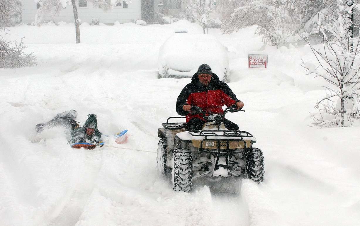 Jim Keech drives a four-wheeler pulling Robin Sumsion and Marin Keech on Claybourne Avenue in Salt Lake City during a snowstorm. Jim said this is the first time he has been able to do this since 1993. (Photo: Ravell Call, Deseret News)