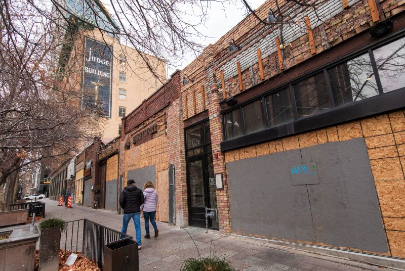People walk past boarded-up businesses on Main Street in Salt Lake City on Monday. Five businesses ...