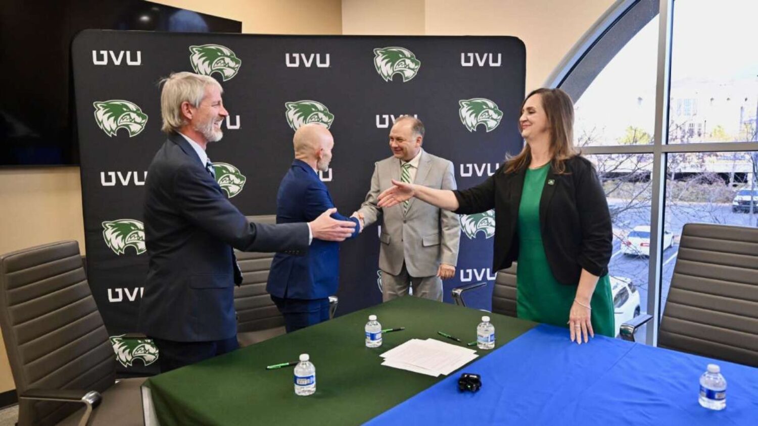 Curtis Larsen, Jamie Cooper, Wayne Vaught, and Michelle Kearns shake hands after signing a memorand...