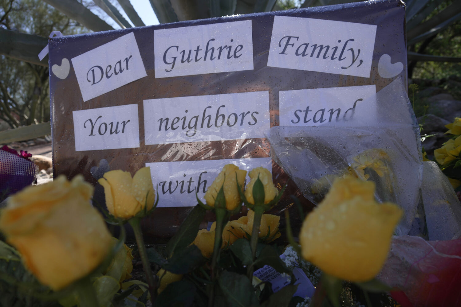 Yellow flowers and signs remain at a vigil outside of Nancy Guthrie’s home on Saturday, Feb. 14, ...