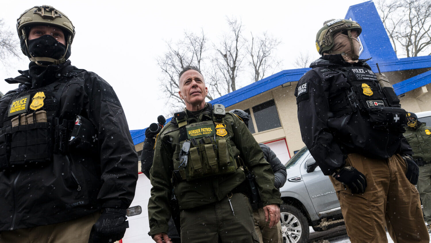 U.S. Border Patrol Commander Gregory Bovino (C) looks on as he is confronted by community members o...