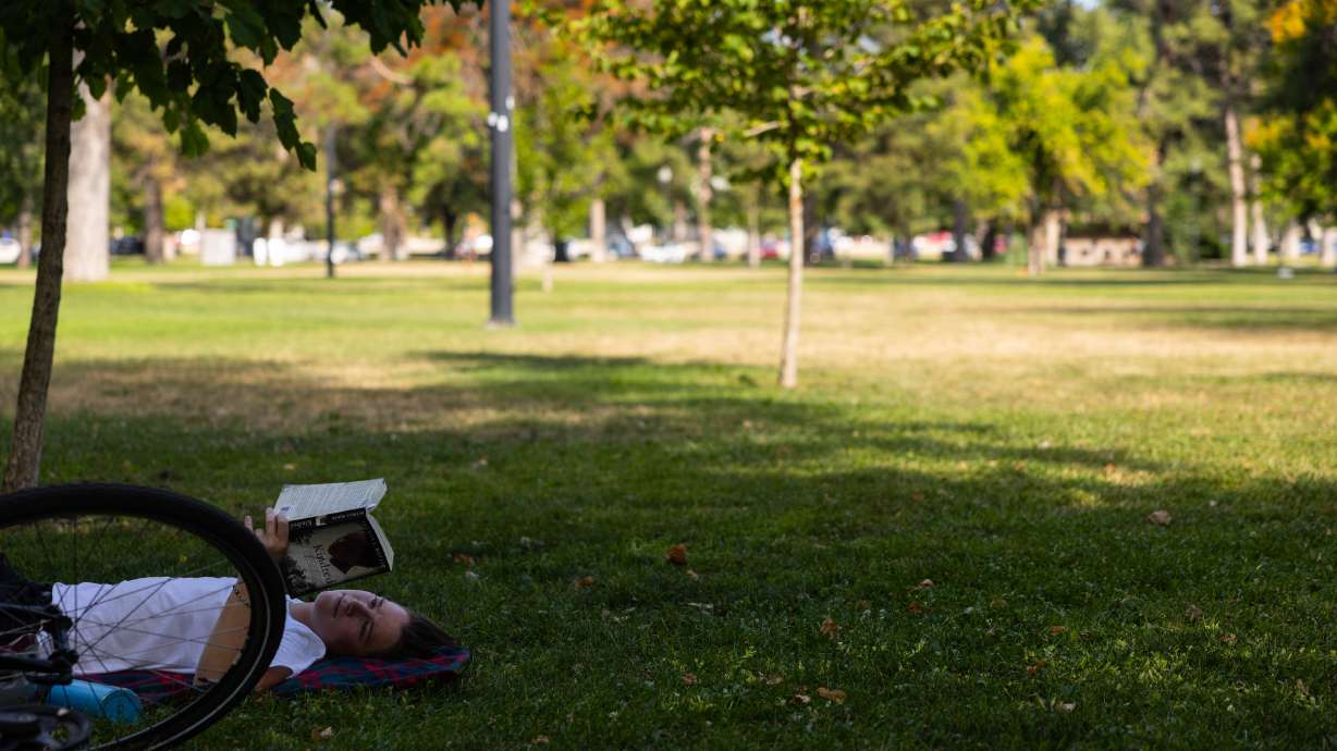 Alexa Dlouhy, 30, reads a book in the shade during a citywide heat advisory at Liberty Park in Salt...