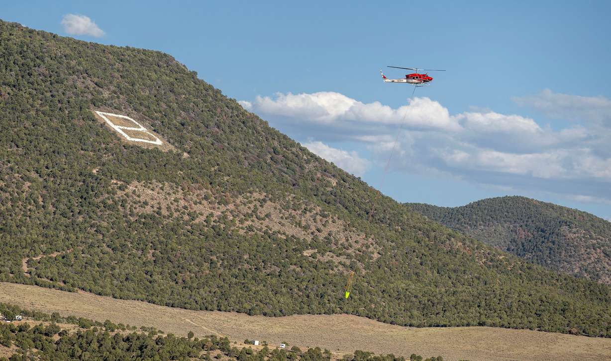 A helicopter flies over the “B” on the hillside as it heads back for more water to drop on the Cottonwood Fire that continues to burn east of the town of Beaver on Tuesday. The fire is the largest nationwide and in the state. (Photo: Scott G Winterton, Deseret News)
