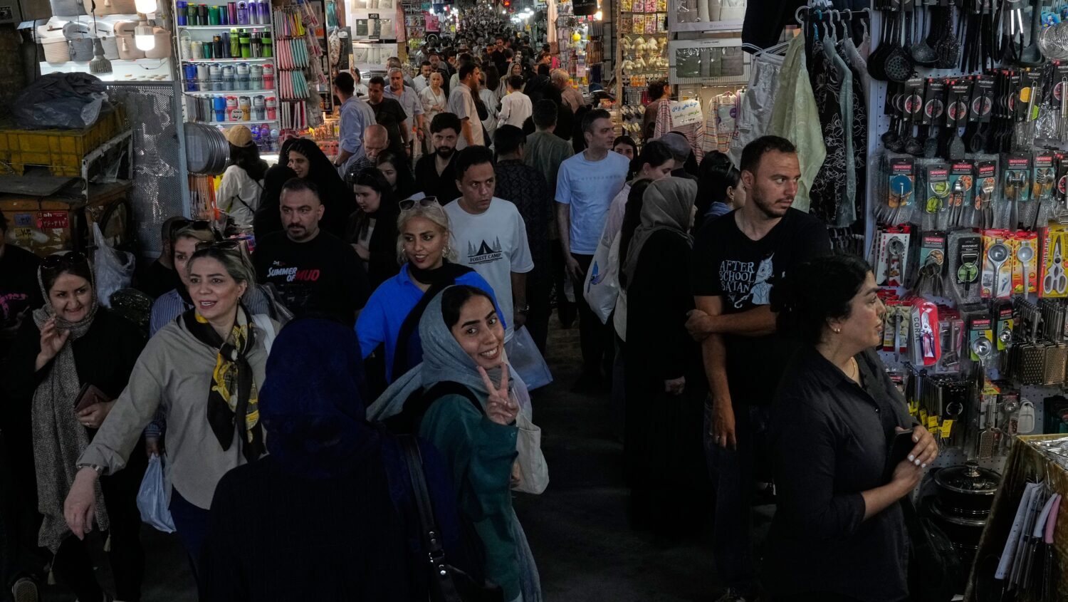 A woman flashes a victory sign while walking at Tehran's traditional main bazaar, Iran, Thursday, J...