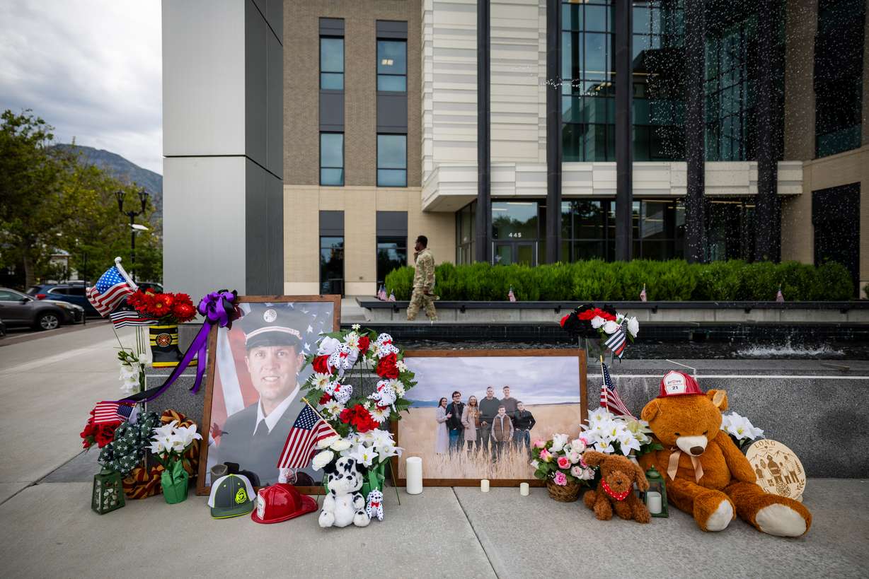 A memorial with flowers, stuffed animals and photos for Provo Fire Capt. Spencer Long and four members of his family who were killed in a flash flood during a weekend camping and hiking trip in Wayne County, outside of City Hall in Provo on July 22. (Photo: Tess Crowley, Deseret News)