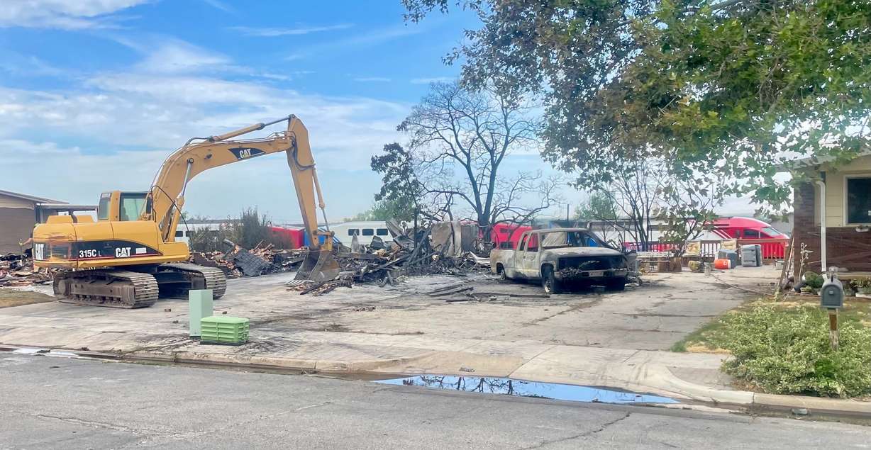 A FrontRunner train on Tuesday passes behind the charred remains of a Roy home destroyed in a fire a day earlier. One fire official suspects sparks from a passing train may be the culprit though authorities are still investigating. (Photo: Tim Vandenack, KSL)