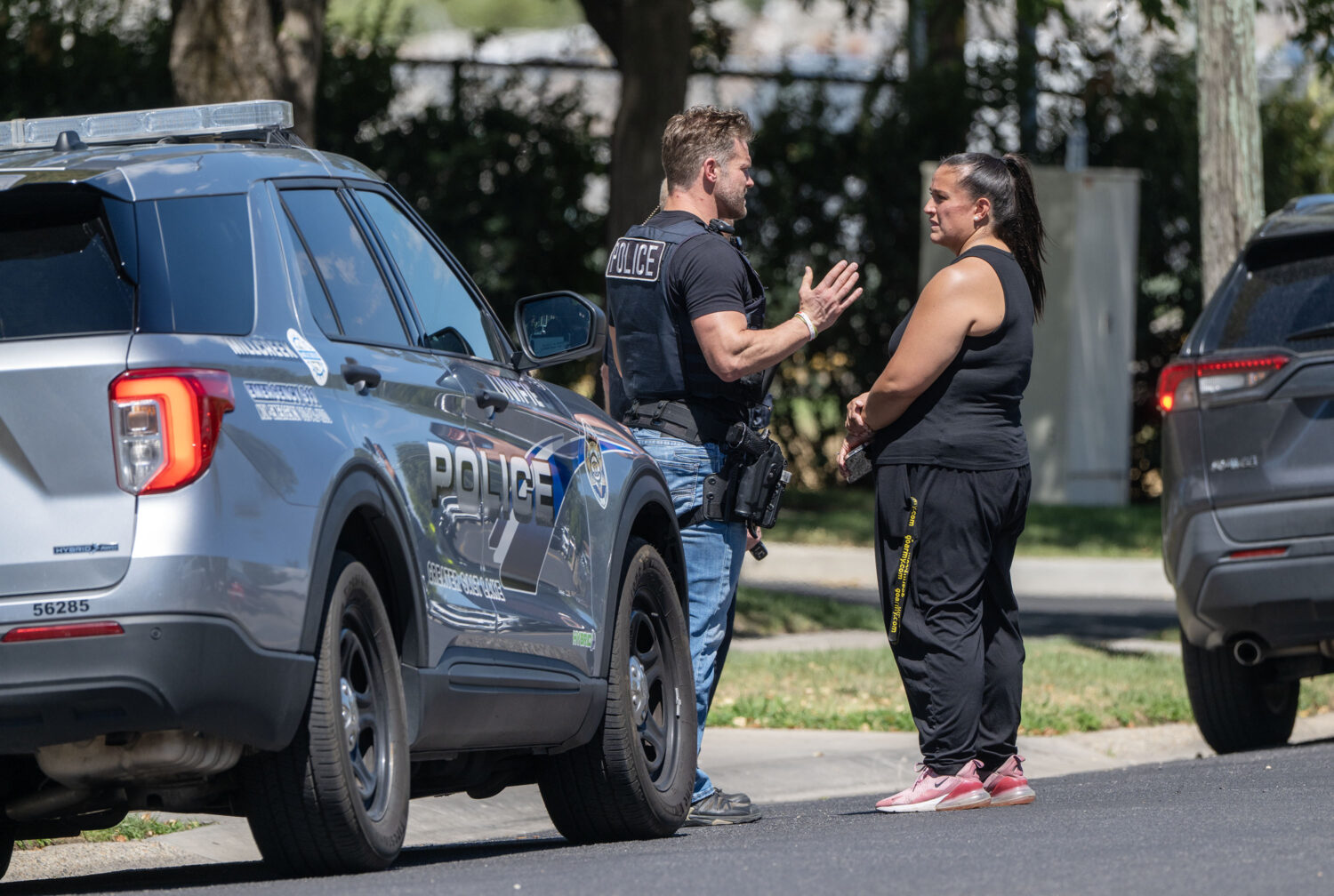 A police officer speaks to a woman as they investigate a shooting that occurred in Kearns during a funeral on Monday, Aug. 17, 2026. (Scott G Winterton, Deseret News)