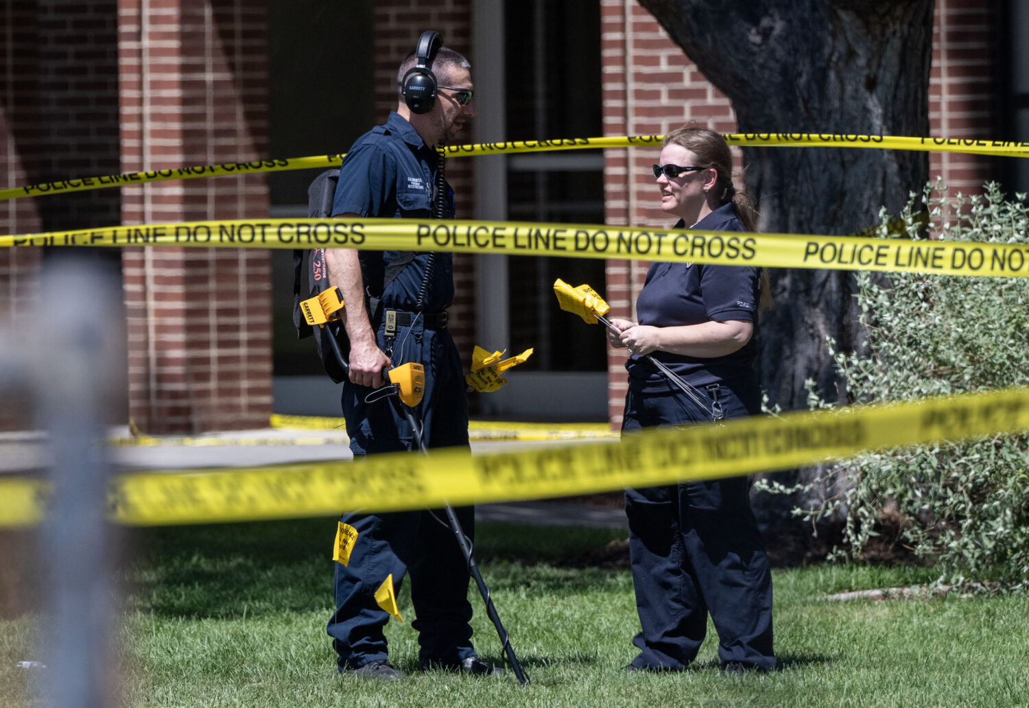 Members of the Forensics Unit use a metal detector to search for evidence as police investigate a s...